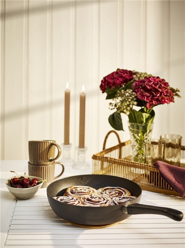 SCANPAN Classic Induction Schmorpfanne mit zubereitetem Gericht vor dunklem Hintergrund