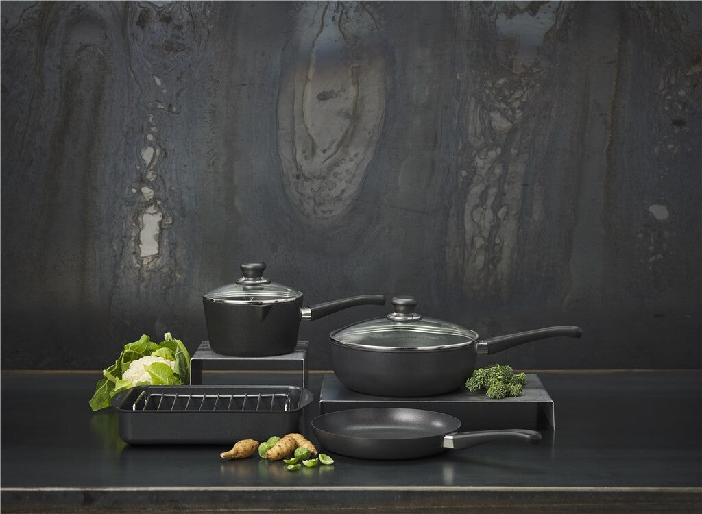 SCANPAN Classic gryder og pander opstillet med grøntsager på mørkt køkkenbord